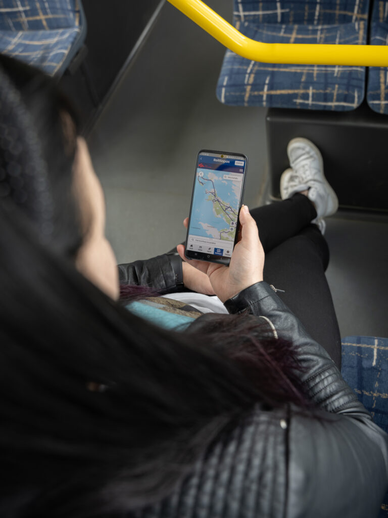 matkustaja katsomassa puhelimensa näytöltä mobiilisovelluksen reittiopasta jossa bussien reitit näkyvät kartalla