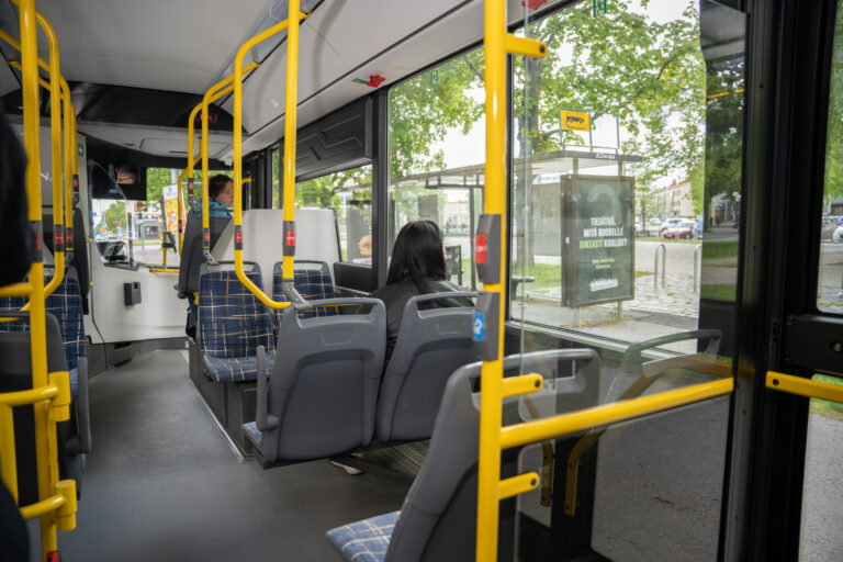 matkustaja matkustaa bussissa, katselee ulos ikkunasta.