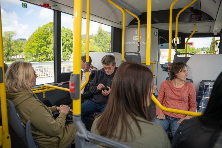 ihmisiä matkustamassa bussissa kesällä